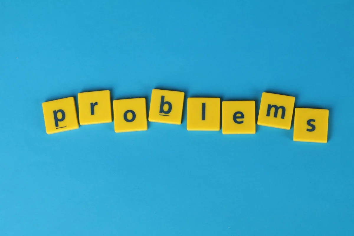 Yellow letter tiles spelling 'problems' arranged on a vibrant blue background, creating a textual concept image.