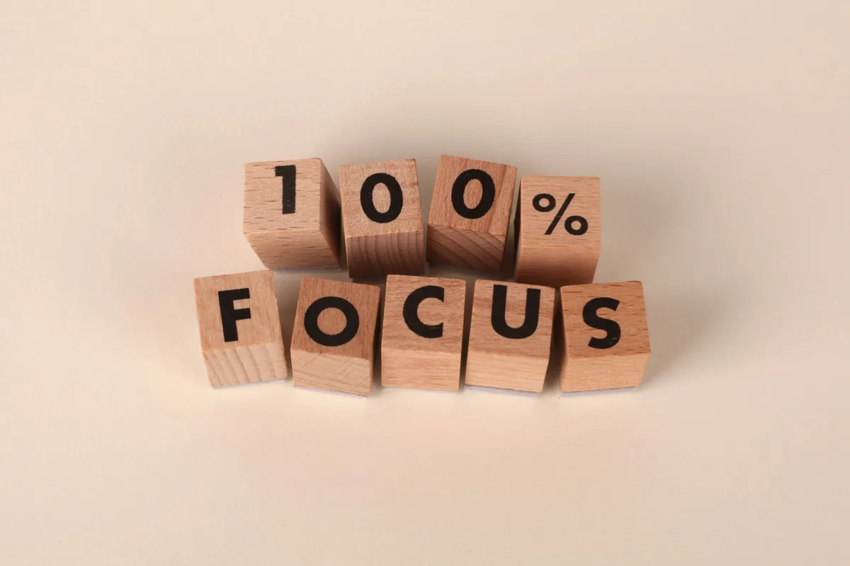 Wooden blocks arranged to spell '100% Focus', representing concentration and dedication.