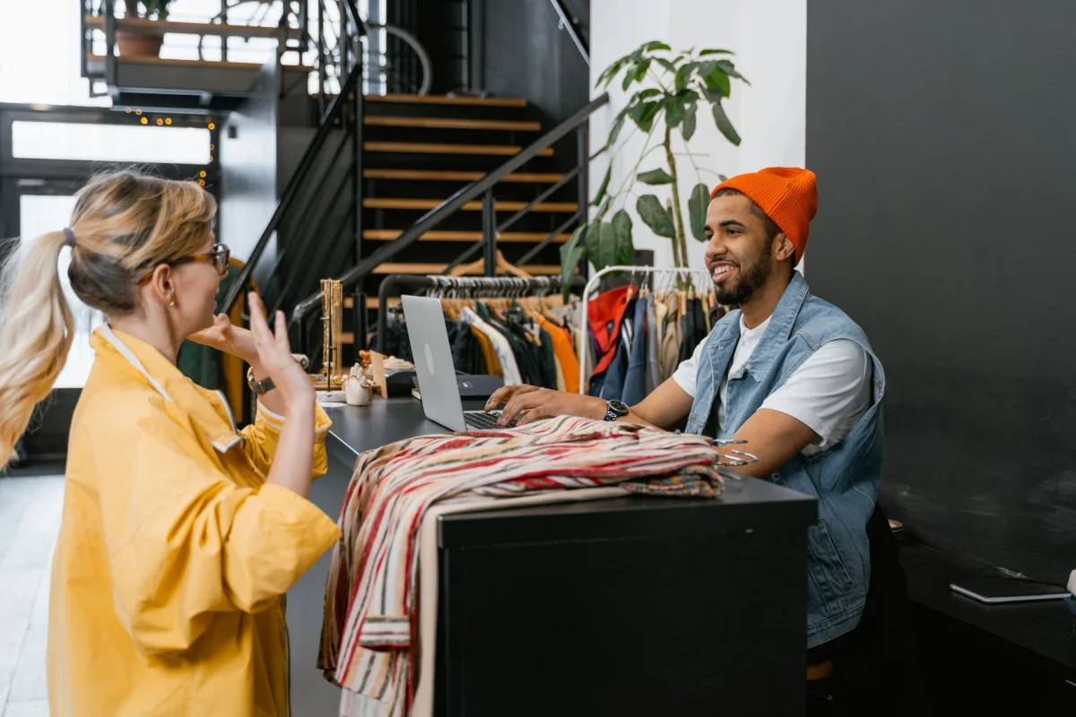 A and clerk engaging in conversation at a fashionable clothing store counter. A and clerk engaging in conversation at a fashionable clothing store counter.