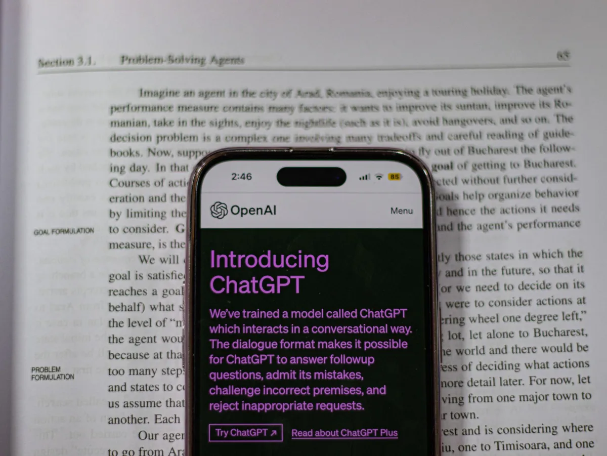 Smartphone showing OpenAI ChatGPT in focus, on top of an open book, highlighting technology and learning. Smartphone showing OpenAI ChatGPT in focus, on top of an open book, highlighting technology and learning.