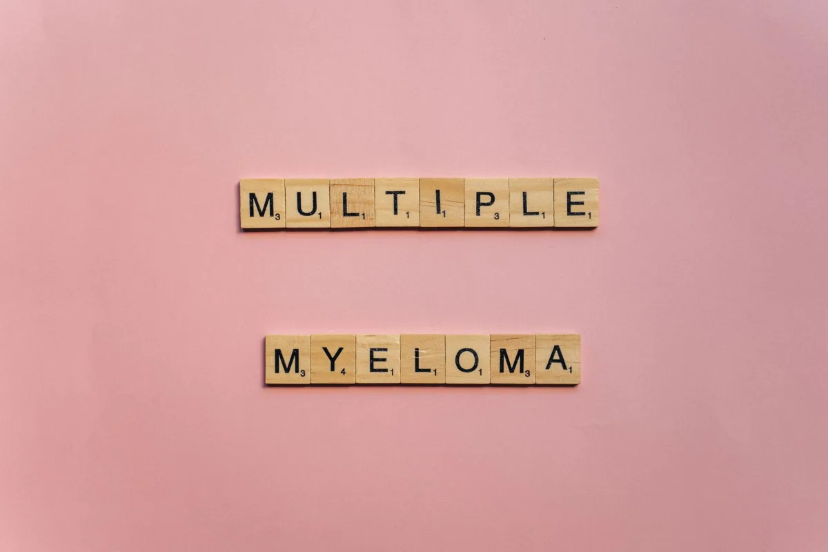 Wooden letter tiles spelling 'Multiple Myeloma' on a pink background.