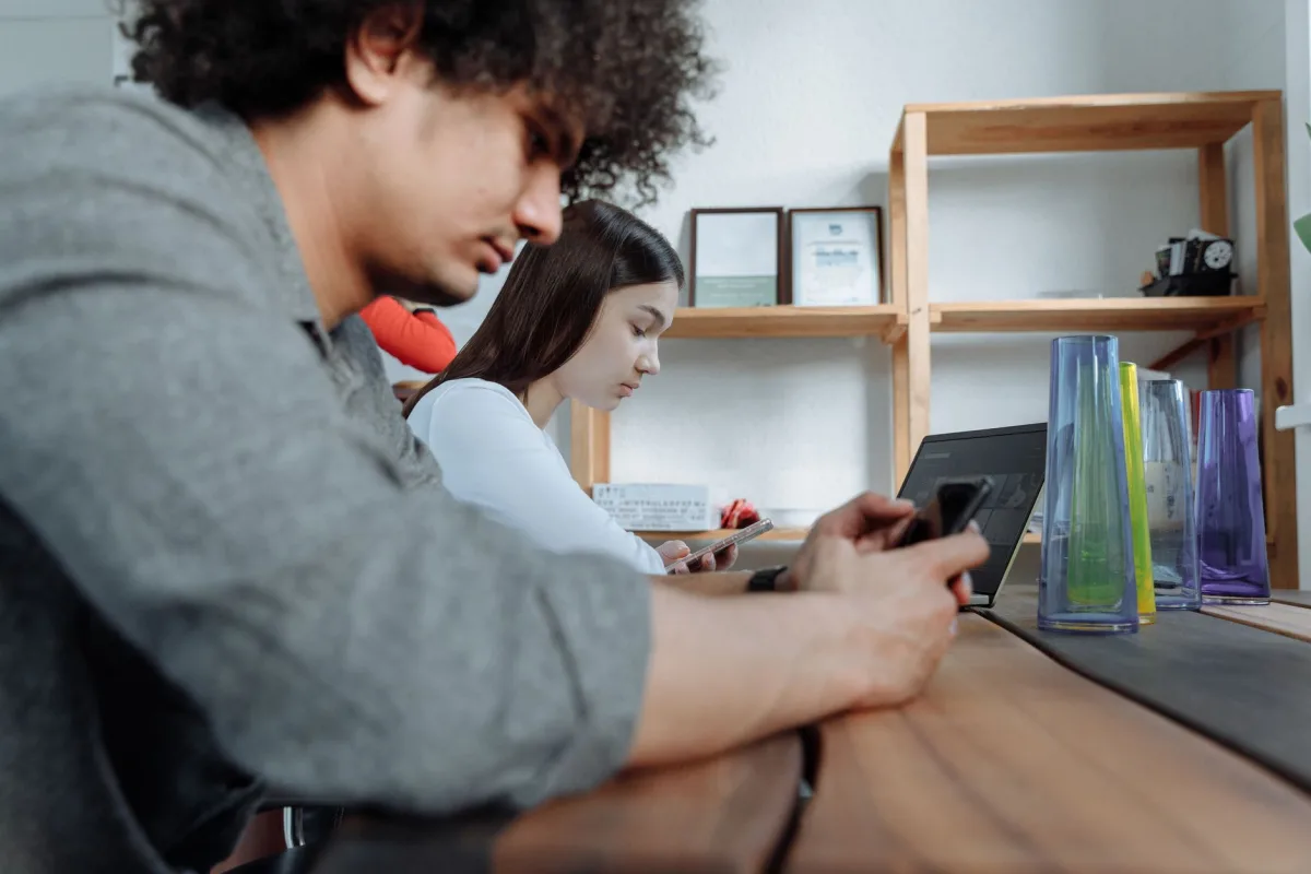 Students focused on smartphones and laptops in a modern classroom setting. Students focused on smartphones and laptops in a modern classroom setting.