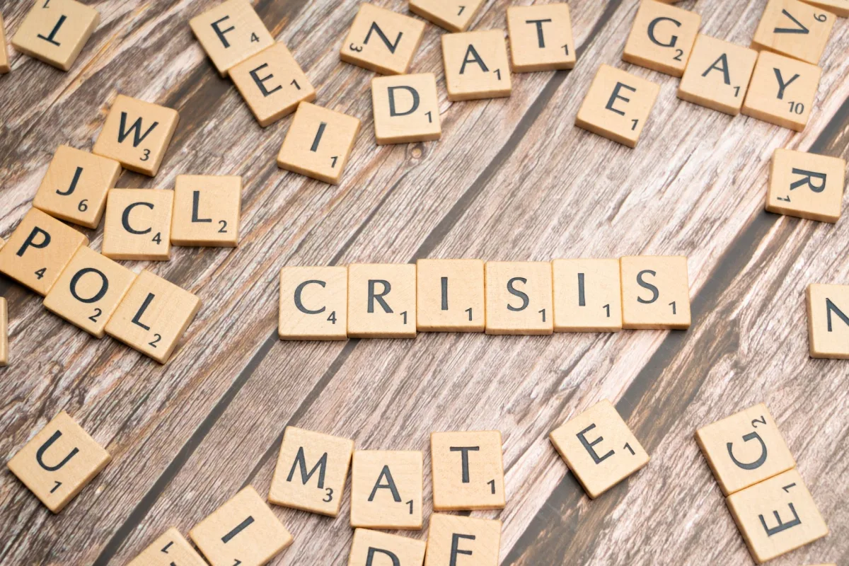 Wooden letter tiles spelling 'Crisis' on a wooden background, conveying a sense of challenge.