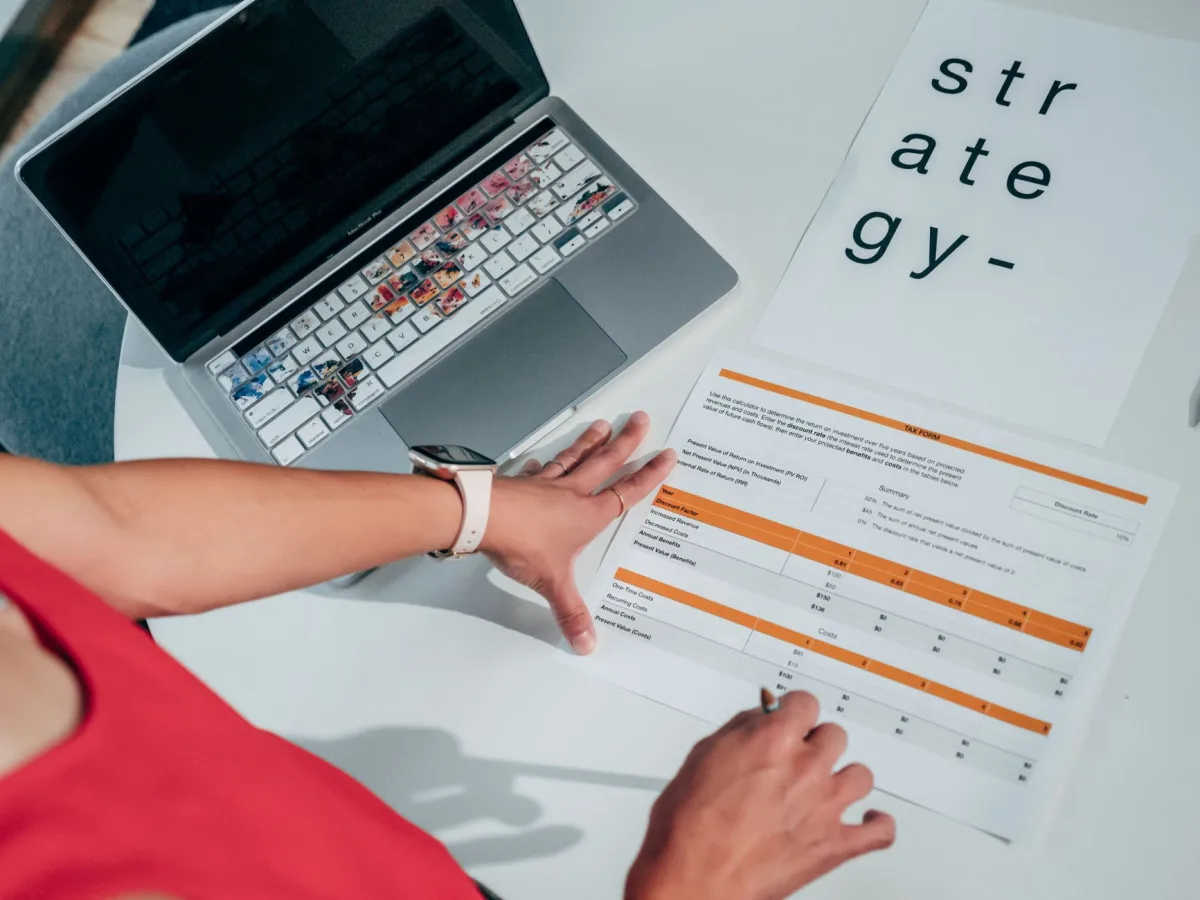 Overhead view of hands on business strategy papers with laptop, highlighting modern planning.