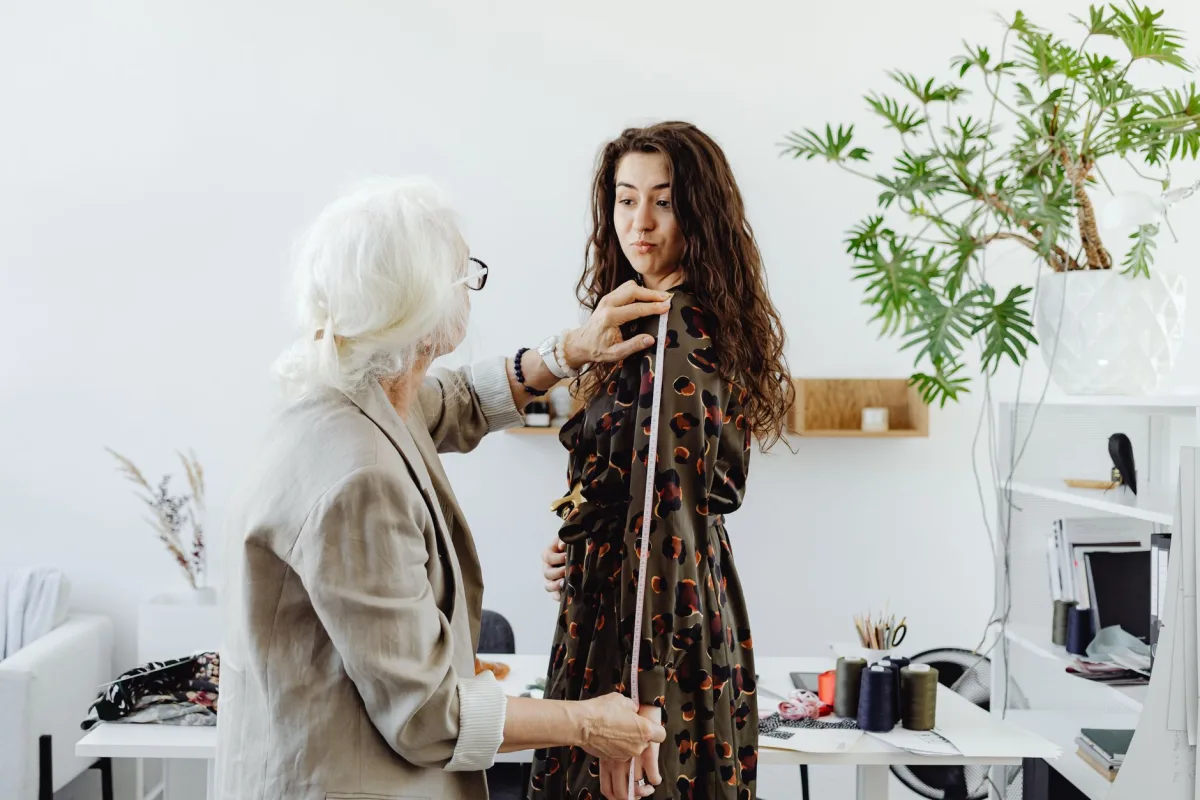 Elderly woman and young woman collaborating an indoor fashion setting with tape. Elderly woman and young woman collaborating an indoor fashion setting with tape.