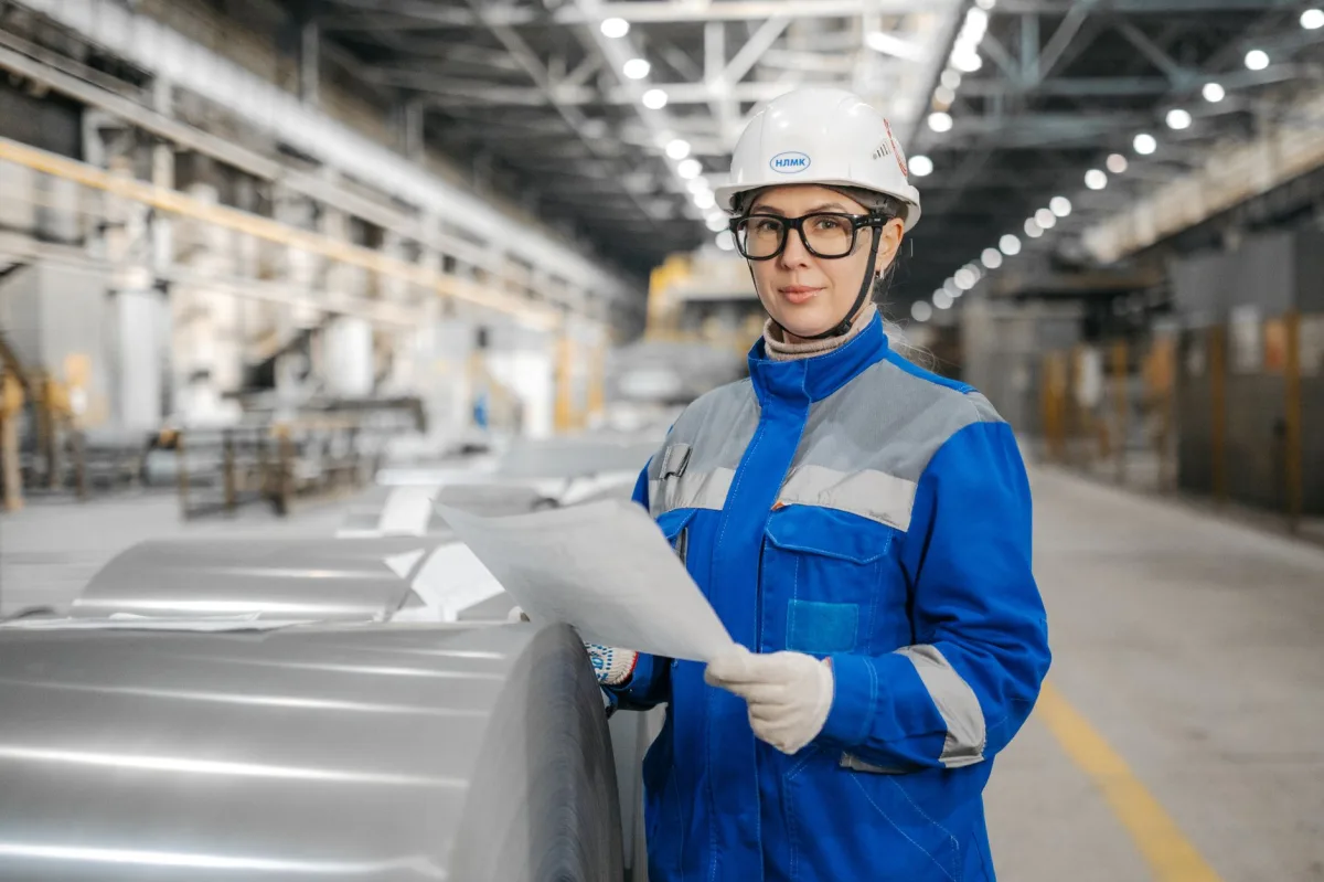 A female engineer wearing safety gear inspects machinery in an industrial factory setting. A female engineer wearing safety gear inspects machinery in an industrial factory setting.
