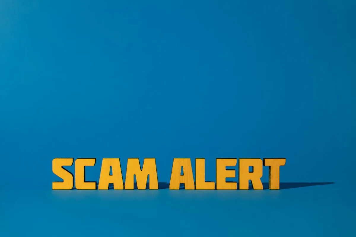 Bold yellow 'Scam Alert' text on a vivid blue surface, emphasizing warning caution. Bold yellow 'Scam Alert' text on a vivid blue surface, emphasizing warning caution.