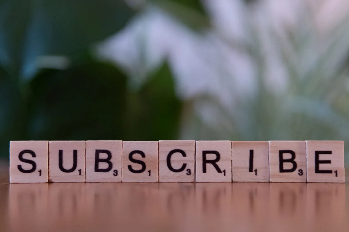 Close-up of the word 'SUBSCRIBE' spelled with wooden letter tiles on a table. Close-up of the word 'SUBSCRIBE' spelled with wooden letter tiles on a table.