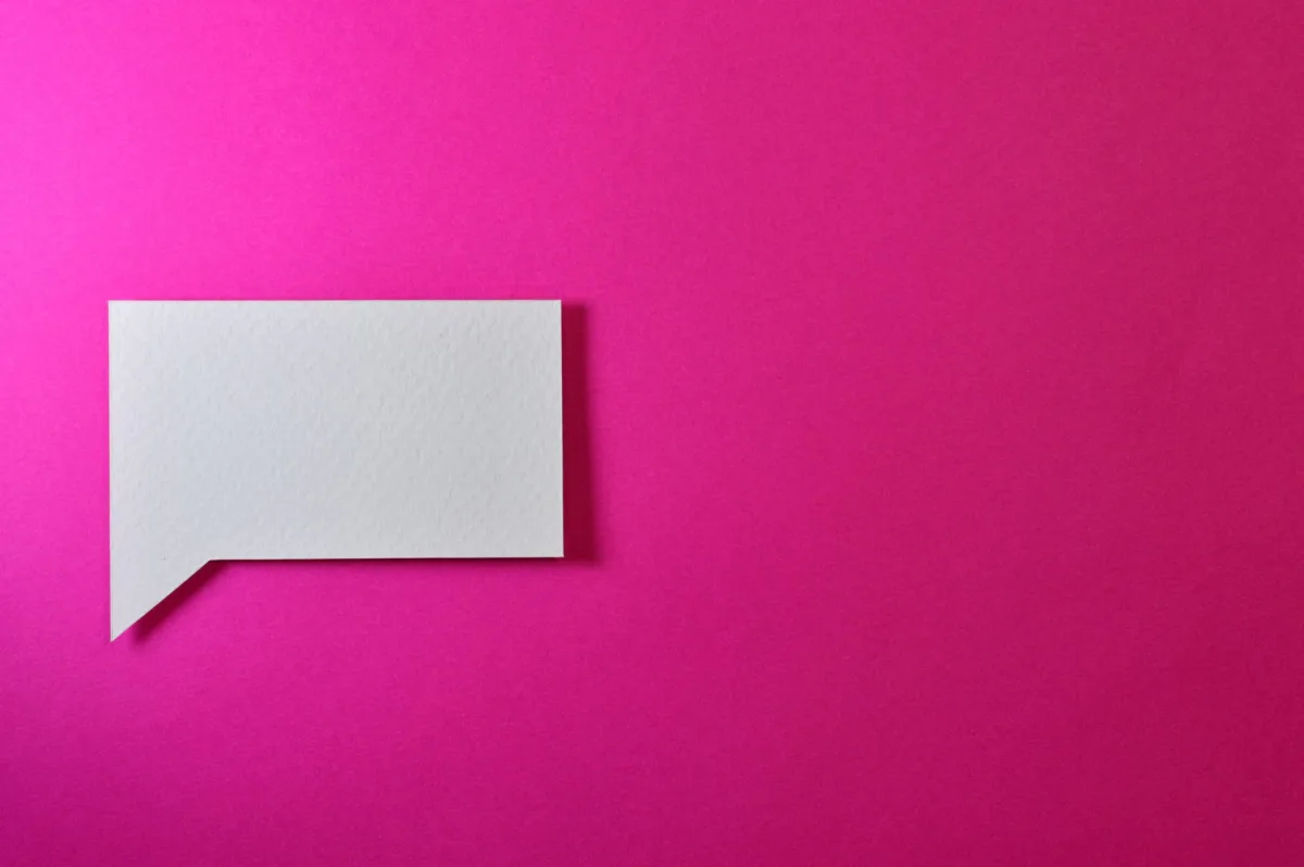 A minimalistic white paper speech bubble on a vibrant pink background, perfect for design projects. A minimalistic white paper speech bubble on a vibrant pink background, perfect for design projects.