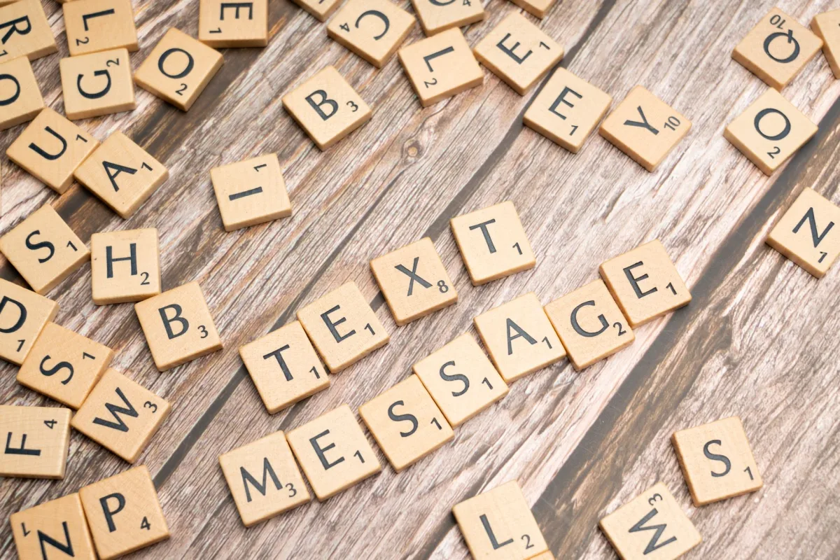 Wooden letter tiles arranged on a wooden surface spelling out 'TEXT MESSAGE'. Wooden letter tiles arranged on a wooden surface spelling out 'TEXT MESSAGE'.