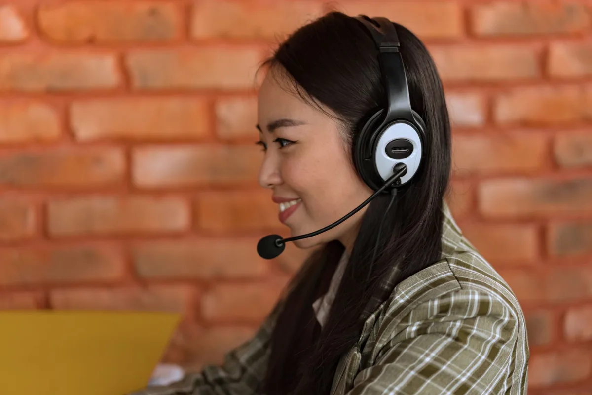 Side view of an Asian woman wearing a headset working in an indoor office environment. Side view of an Asian woman wearing a headset working in an indoor office environment.