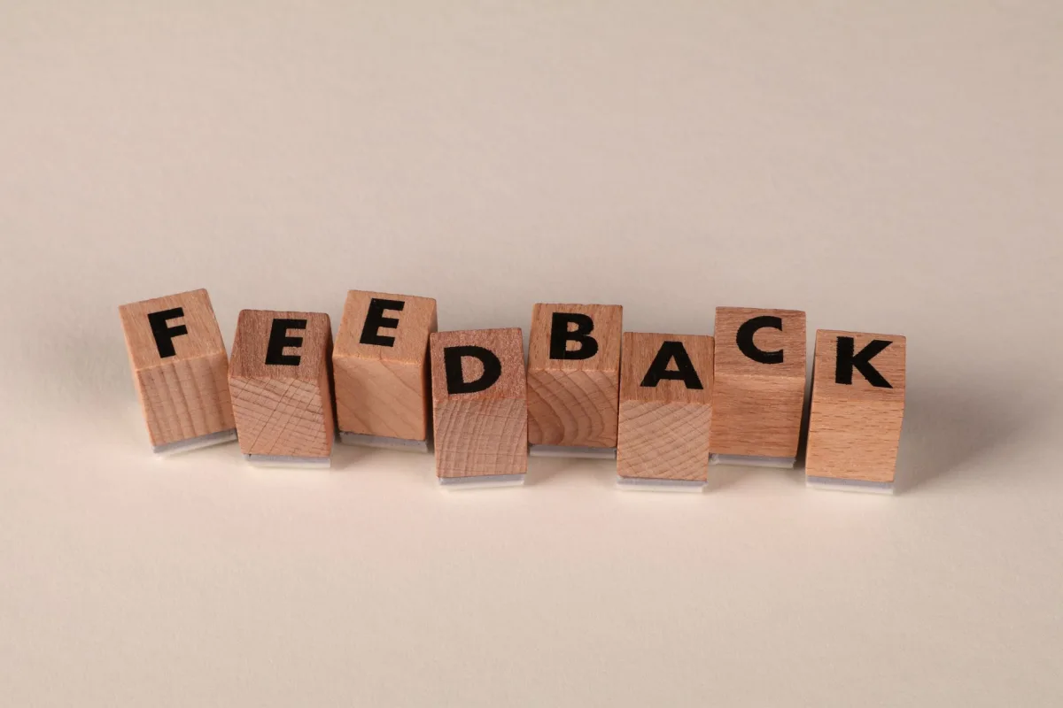 Wooden letter blocks arranged to spell 'FEEDBACK' on a neutral background. Ideal communication concepts.