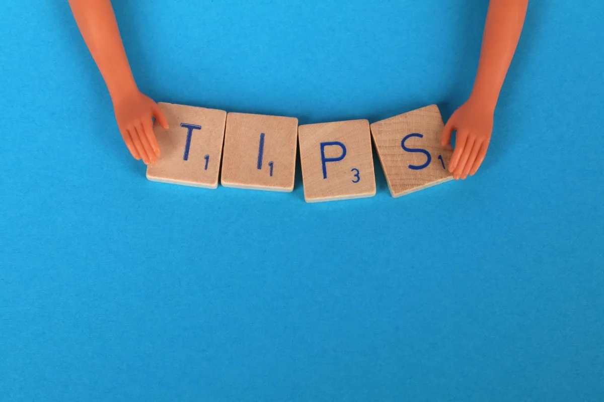 Scrabble tiles spelling 'TIPS' on a blue background, ideal creative concepts.