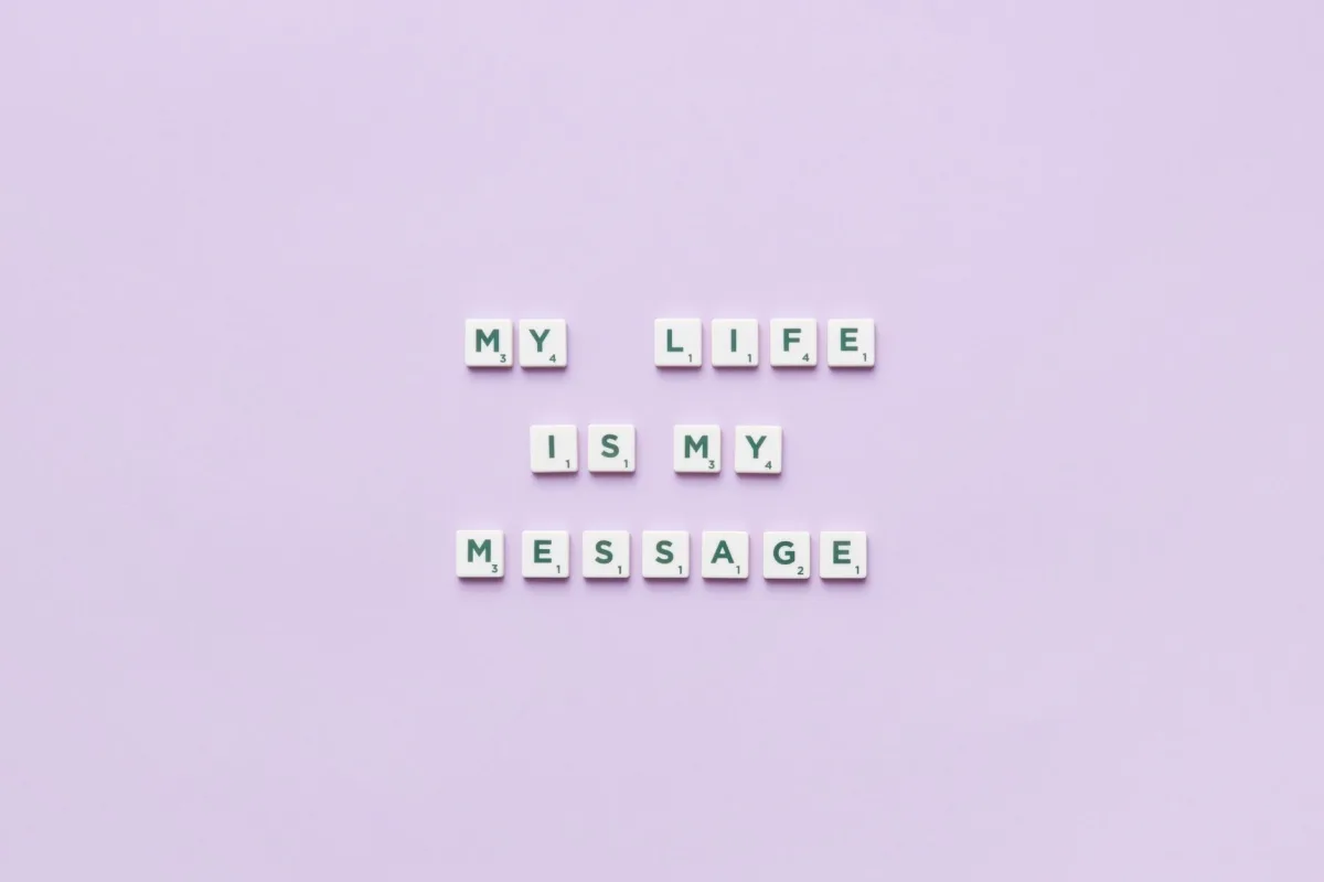 Scrabble tiles spell 'My life is my message' on a pastel purple background.