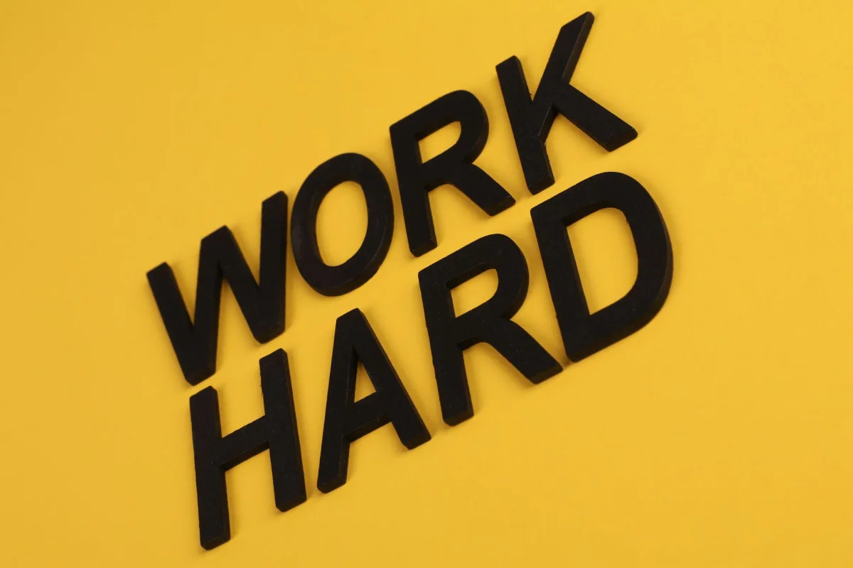 Black text 'Work Hard' on a vibrant yellow background for motivation. Black text 'Work Hard' on a vibrant yellow background for motivation.