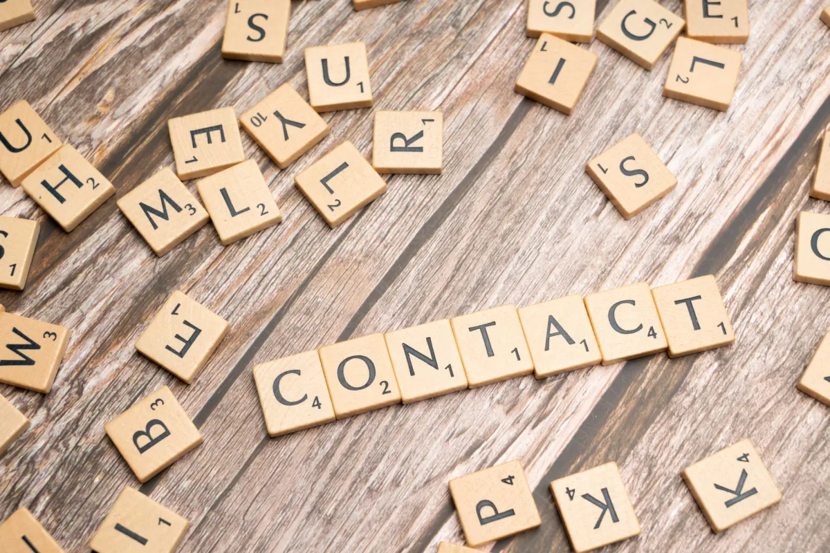 Scrabble-style letter tiles spelling 'contact' on wooden surface. Scrabble-style letter tiles spelling 'contact' on wooden surface.