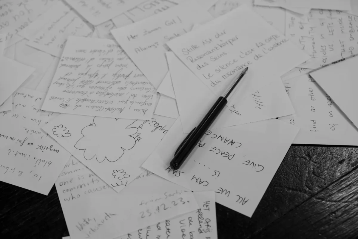 A collection of handwritten notes scattered on a desk with a pen in black and white. A collection of handwritten notes scattered on a desk with a pen in black and white.