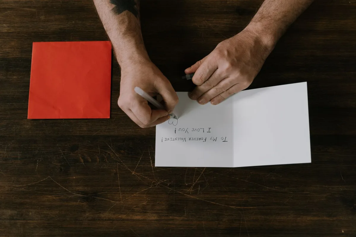 Man a romantic message on a card with a red envelope, top view. Man a romantic message on a card with a red envelope, top view.
