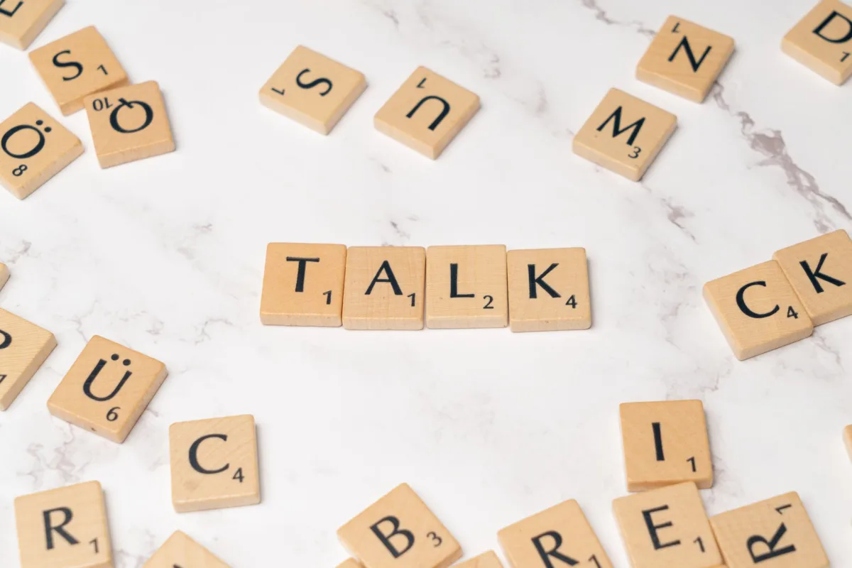 Wooden Scrabble tiles on a marble background spelling 'Talk', symbolizing communication and language. Wooden Scrabble tiles on a marble background spelling 'Talk', symbolizing communication and language.