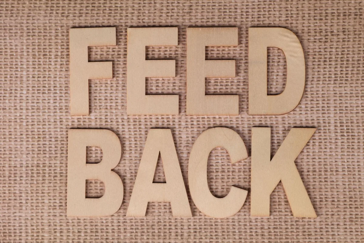 Wooden letters spelling 'FEEDBACK' on a burlap background, emphasizing communication.