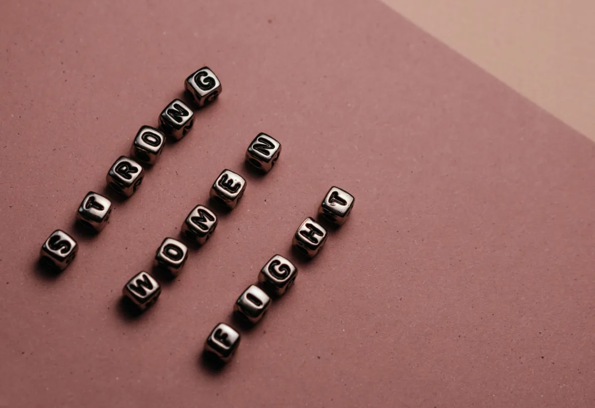 Close-up of beads spelling 'Strong Women Fight' on a brown background. Close-up of beads spelling 'Strong Women Fight' on a brown background.