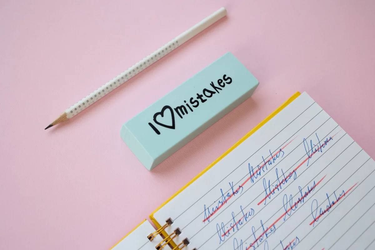 A blue eraser with 'I Love Mistakes' next a pencil and crossed-out text on a pink background.
