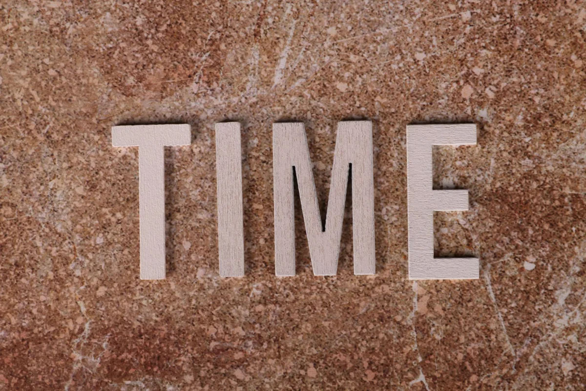 Close-up of the word 'TIME' spelled with wooden letters on a textured surface. Close-up of the word 'TIME' spelled with wooden letters on a textured surface.
