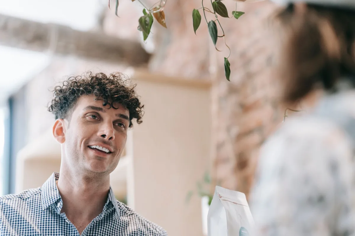 Casual indoor scene of a smiling man with curly hair conversing happily.