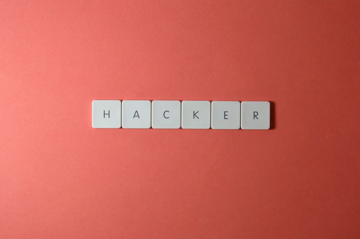 Close-up of the word 'HACKER' made with letter tiles on a red background, emphasizing cybersecurity. Close-up of the word 'HACKER' made with letter tiles on a red background, emphasizing cybersecurity.