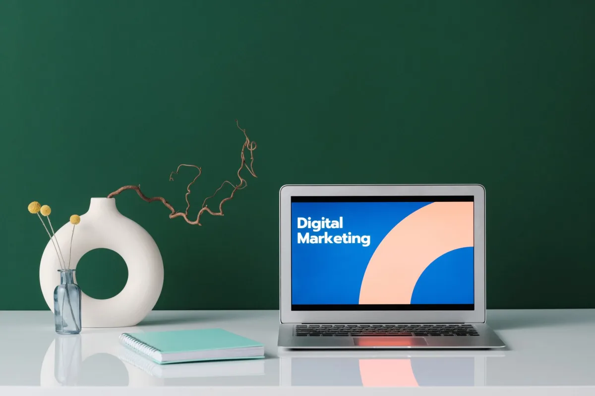 A modern workspace featuring a laptop displaying 'Digital Marketing' against a green wall. A modern workspace featuring a laptop displaying 'Digital Marketing' against a green wall.