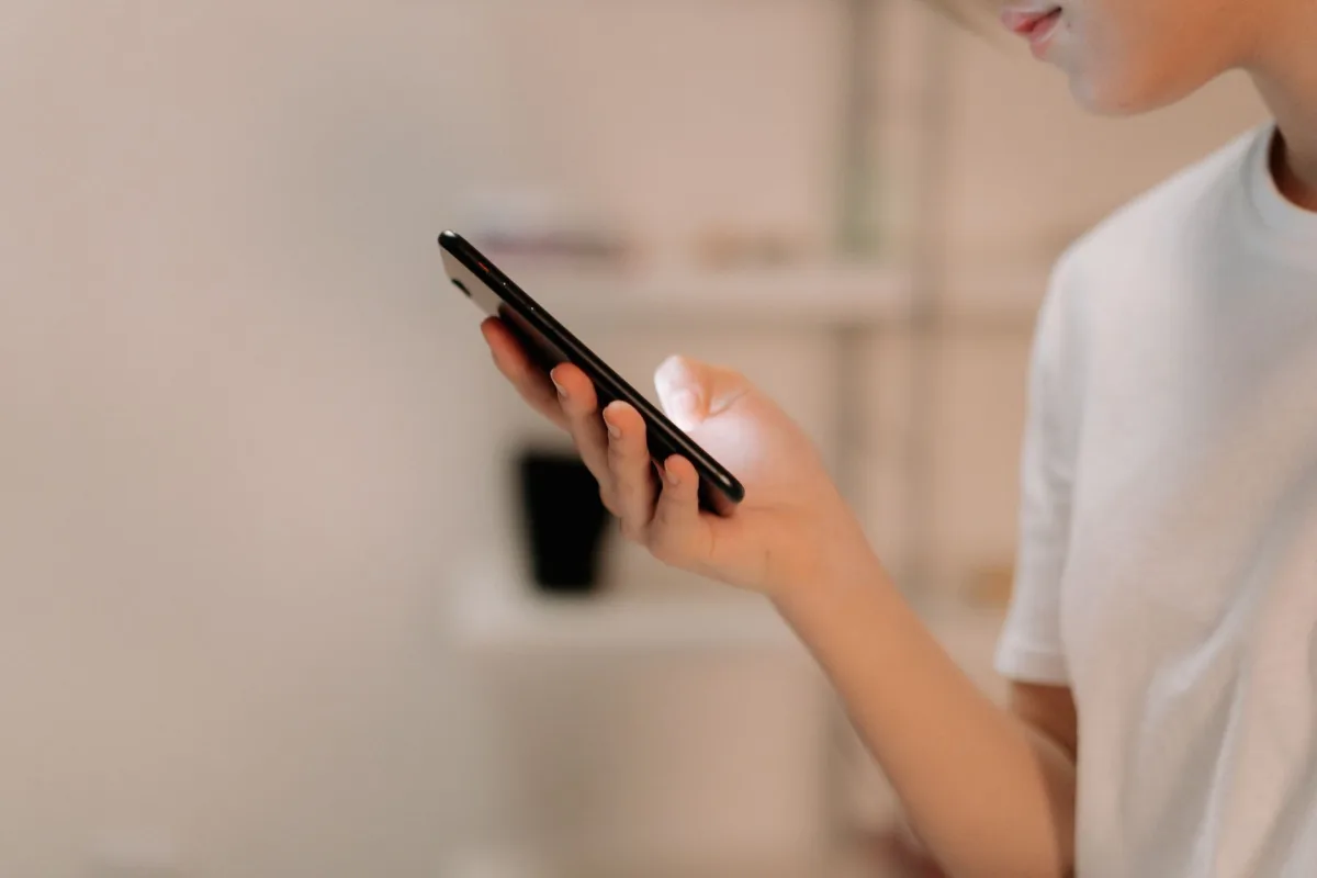 Close-up of a person using a smartphone indoors, focusing on hand and device.