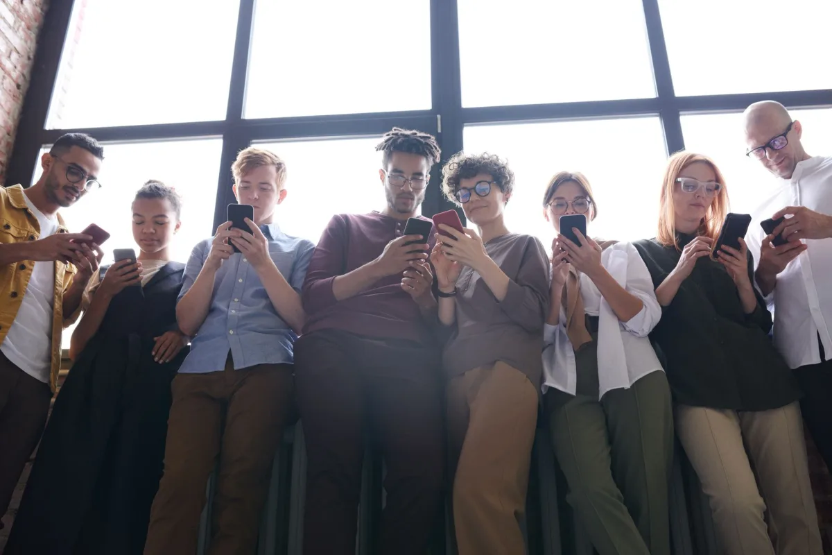 A diverse group of adults using smartphones in a modern indoor setting, fostering social interaction. A diverse group of adults using smartphones in a modern indoor setting, fostering social interaction.