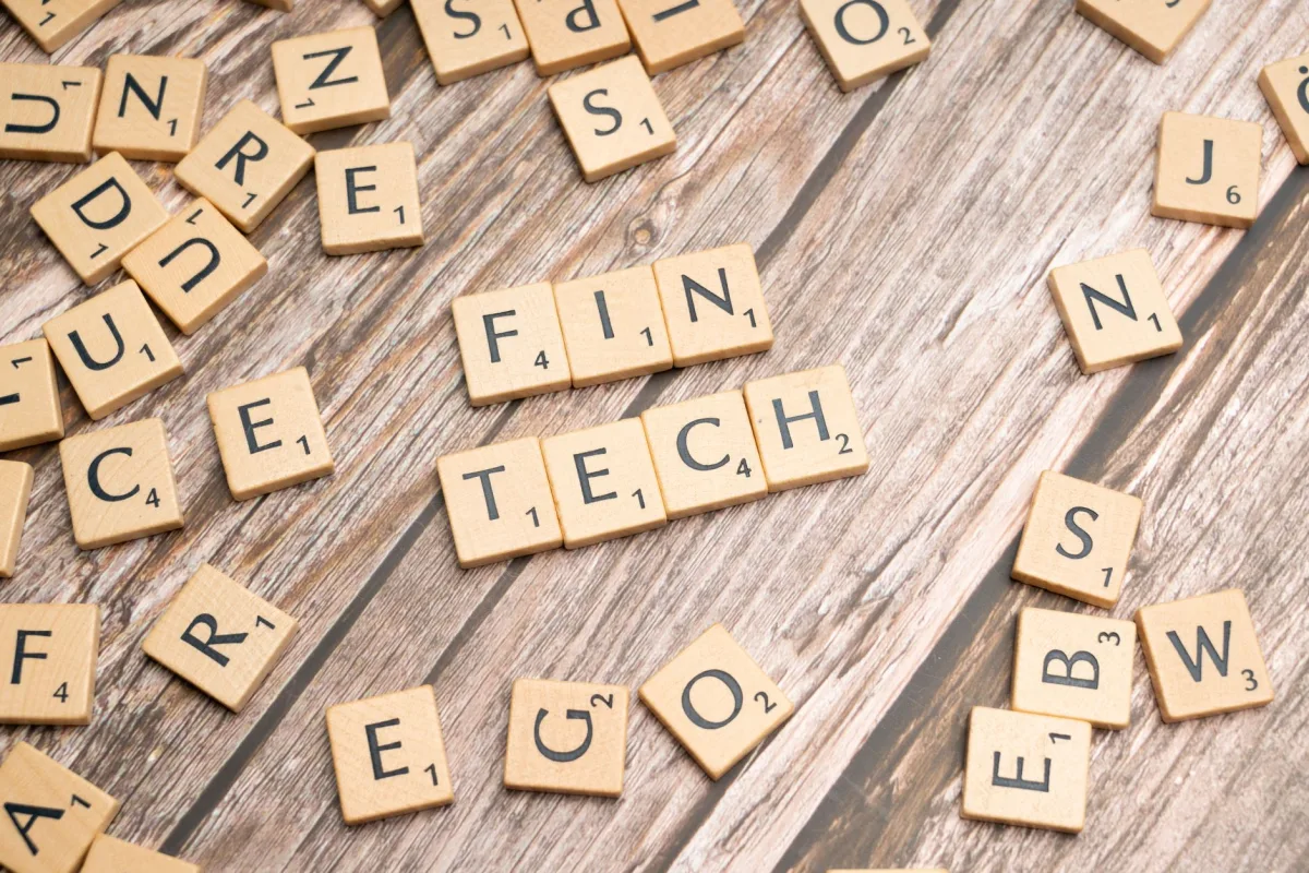 Fintech spelled out with wooden letter tiles on a rustic wooden background. Fintech spelled out with wooden letter tiles on a rustic wooden background.