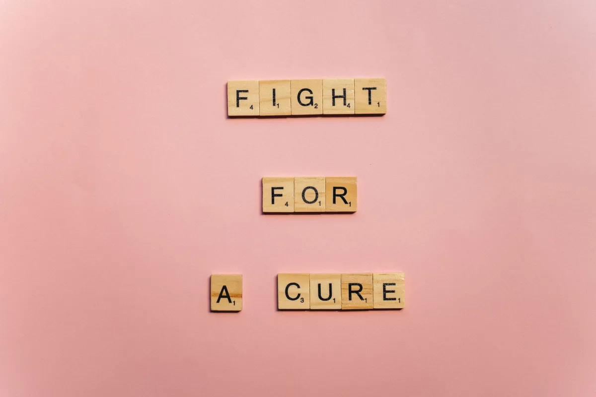 Wooden letter tiles on a pink background spell 'Fight for a Cure'. Motivational design. Wooden letter tiles on a pink background spell 'Fight for a Cure'. Motivational design.