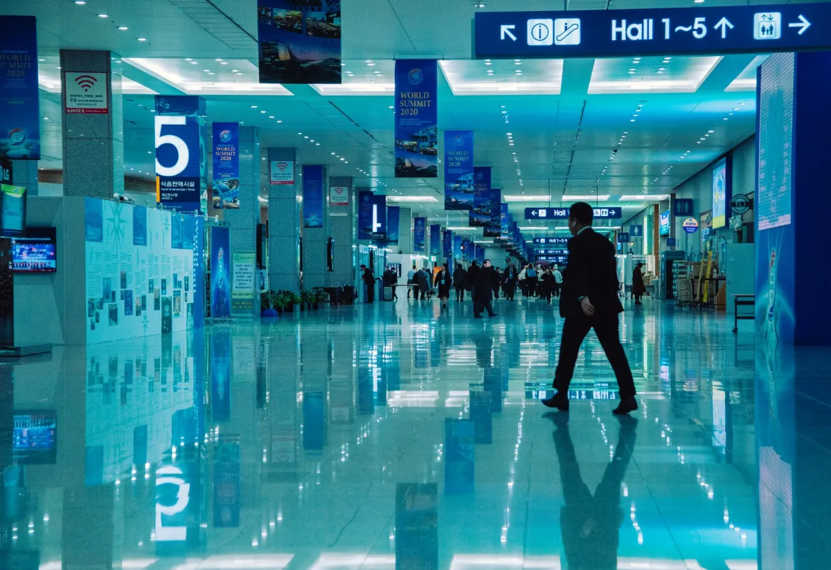 An indoor view of a busy conference hall during World Summit 2020 with directional signs and reflections. An indoor view of a busy conference hall during World Summit 2020 with directional signs and reflections.