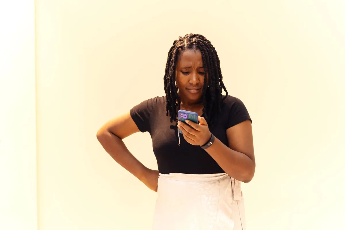 A young woman with braids looks at her phone in Lagos, Nigeria. A young woman with braids looks at her phone in Lagos, Nigeria.