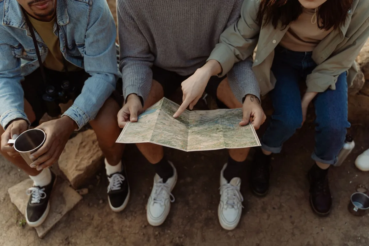 Group of friends sitting together, exploring a map for their next adventure, creating exciting travel plans. Group of friends sitting together, exploring a map for their next adventure, creating exciting travel plans.