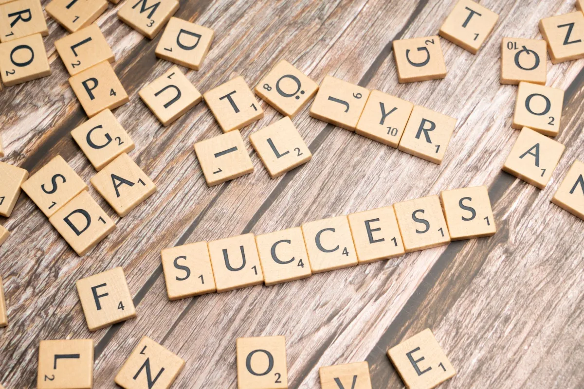 Close-up of wooden letter tiles spelling 'success' on rustic surface, symbolizing achievement and goals. Close-up of wooden letter tiles spelling 'success' on rustic surface, symbolizing achievement and goals.