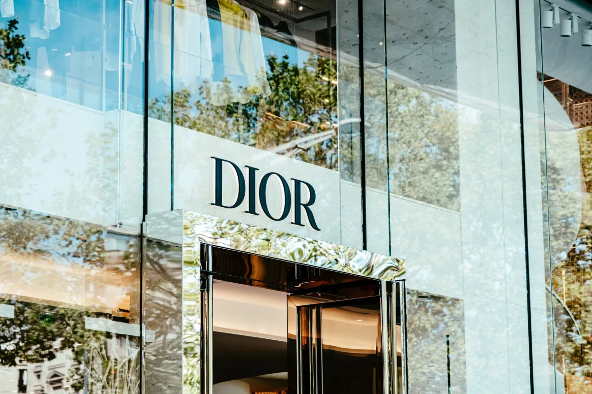 Exterior of a Dior store with glass facade reflecting trees and architecture. Exterior of a Dior store with glass facade reflecting trees and architecture.