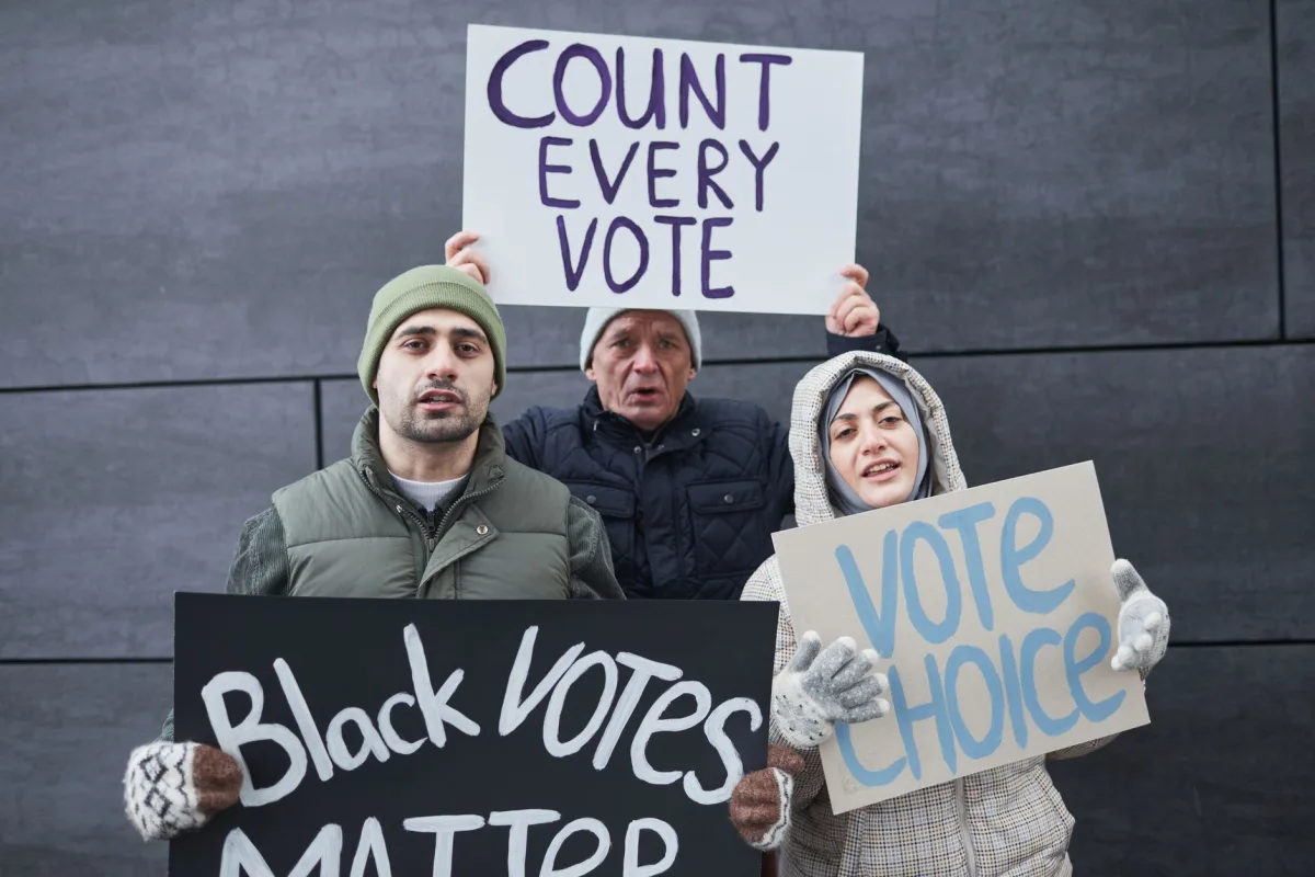 A diverse group of people holding signs advocating for voting rights and equality during a winter outdoor protest. A diverse group of people holding signs advocating for voting rights and equality during a winter outdoor protest.