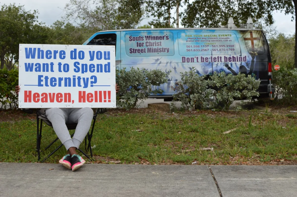 Outdoor scene of a person holding a religious sign about eternity near a parked van. Outdoor scene of a person holding a religious sign about eternity near a parked van.