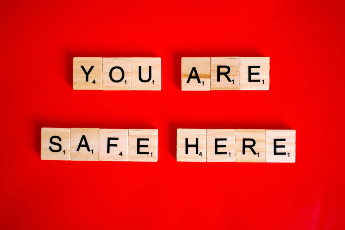 Wooden Scrabble tiles display 'You Are Safe Here' against a red background, symbolizing safety. Wooden Scrabble tiles display 'You Are Safe Here' against a red background, symbolizing safety.