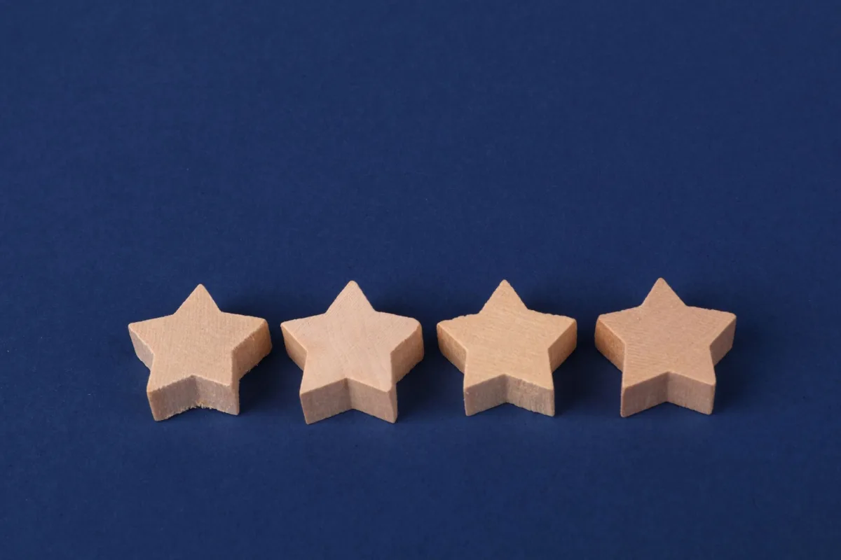 Minimalist photo of four wooden star shapes arranged on a navy blue surface.