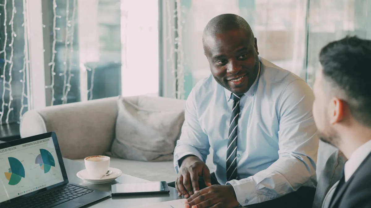 Two businessmen discussing projects over coffee and data charts. Two businessmen discussing projects over coffee and data charts.