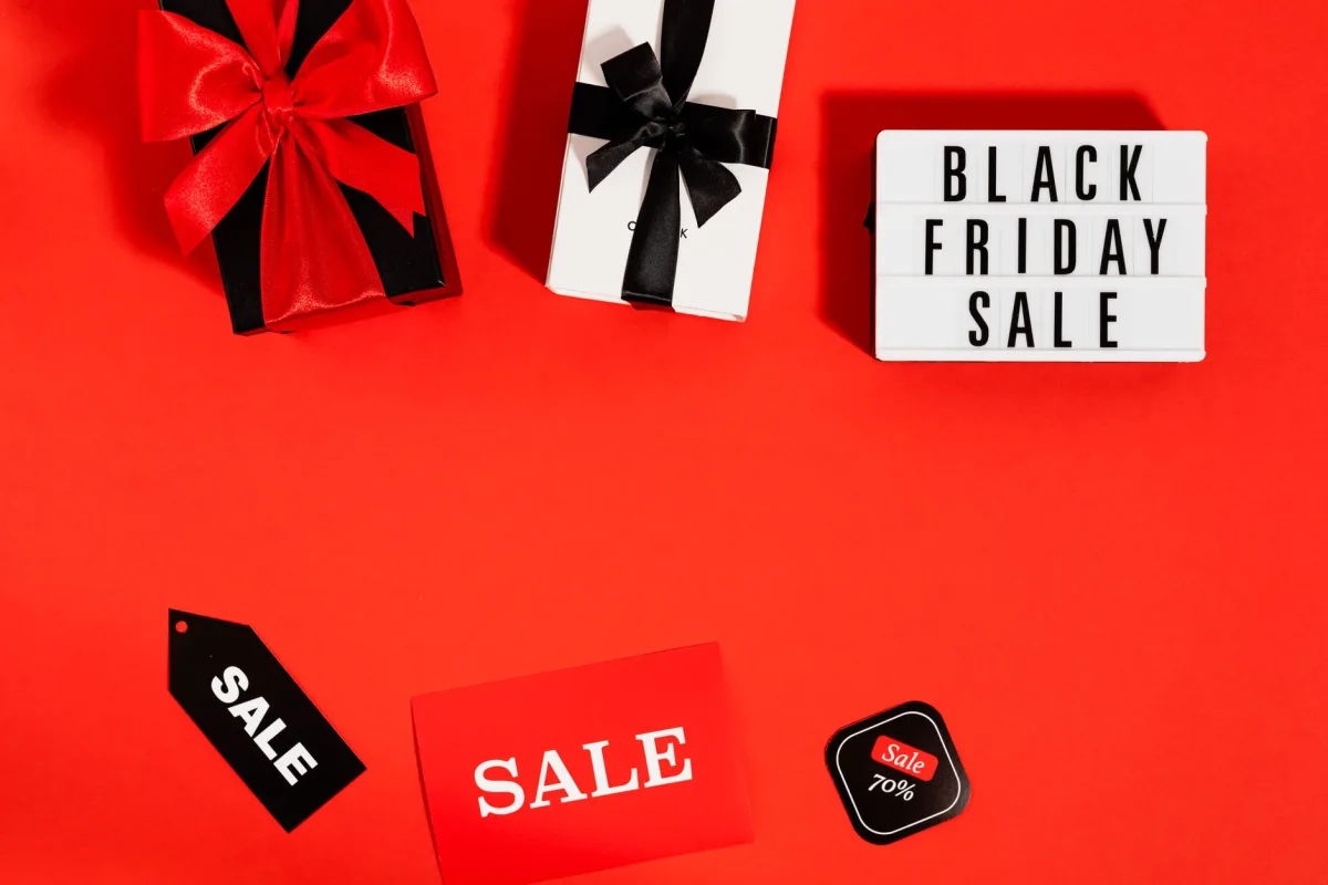 Bright flat lay featuring Black Friday sale items, gift boxes with bows, and sale tags on red background. Bright flat lay featuring Black Friday sale items, gift boxes with bows, and sale tags on red background.