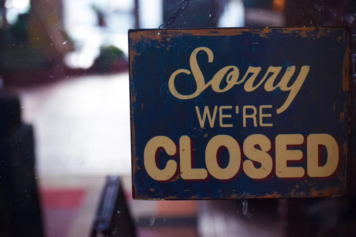 A rustic 'Sorry We're Closed' sign displayed on a shop door, atmospheric lighting. A rustic 'Sorry We're Closed' sign displayed on a shop door, atmospheric lighting.