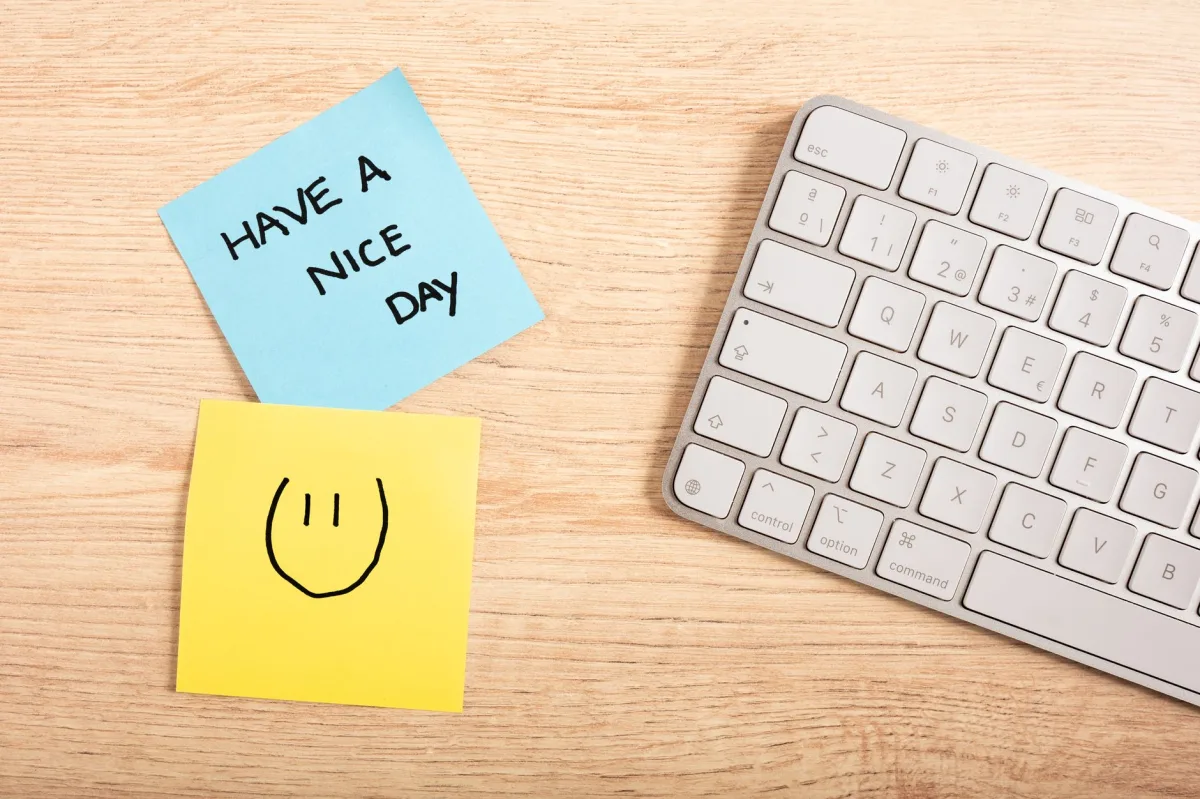 A cheerful desk setup with a note saying 'Have a Nice Day' next to a keyboard. A cheerful desk setup with a note saying 'Have a Nice Day' next to a keyboard.