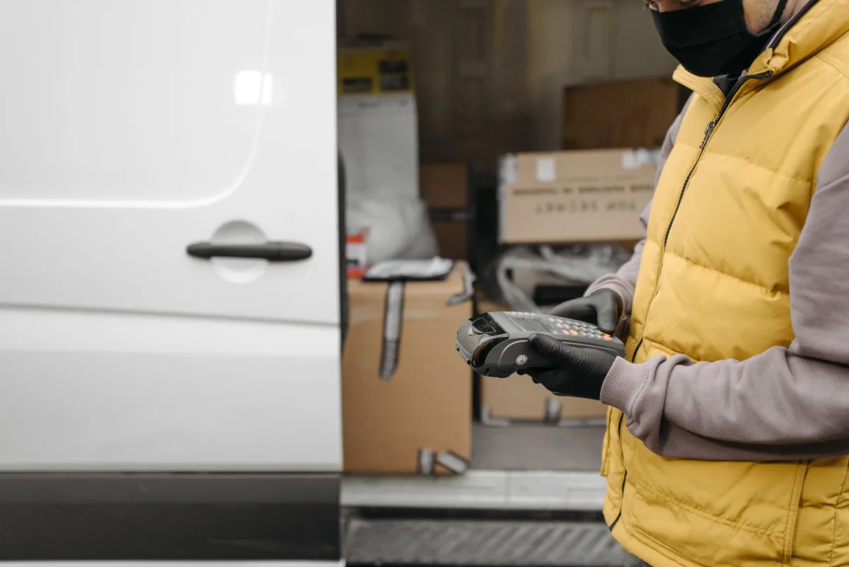 Courier using a terminal contactless delivery payment next to a van with packages. Courier using a terminal contactless delivery payment next to a van with packages.