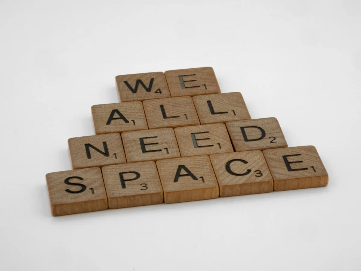 Creative arrangement of wooden letter tiles spelling 'We All Need Space' on a white background.