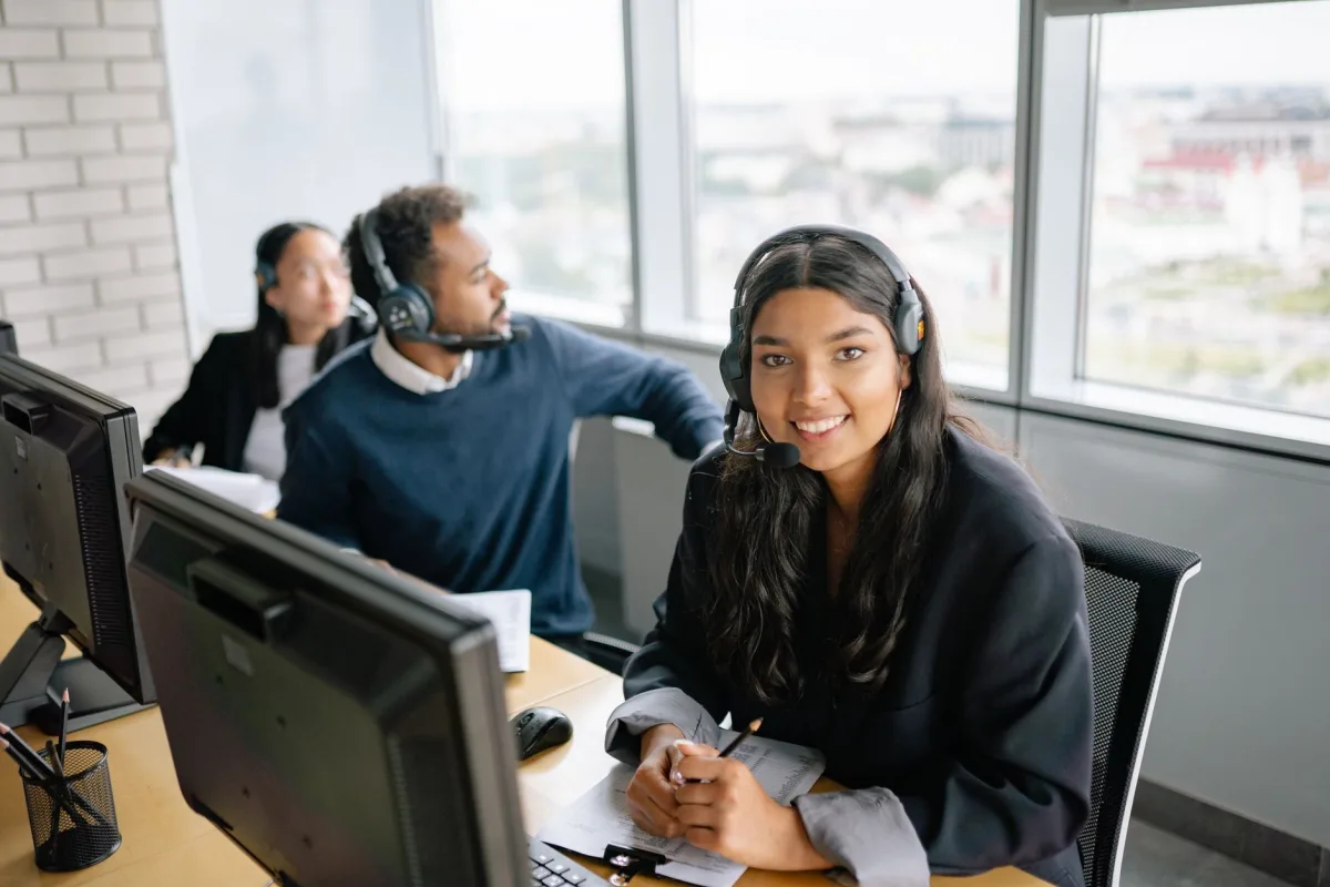 Smiling call center agents working together in a bright office environment.